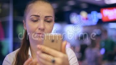 一个年轻的女人坐在快餐店里，拍自拍，在智能<strong>手机屏幕</strong>上看她的<strong>照片</strong>。
